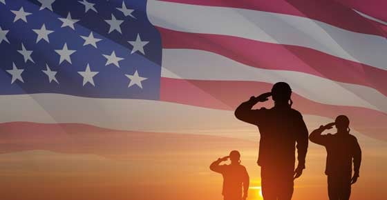 Silhouettes of soldiers saluting on background of sunset or sunrise and USA flag. 