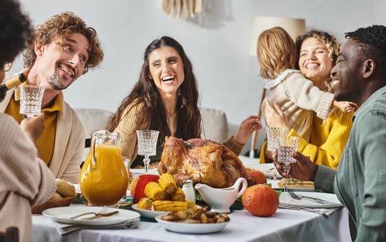happy multicultural family and friends having holiday dinner together on Thanksgiving day