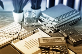 Office desk with glasses, calculator, paperwork and planner